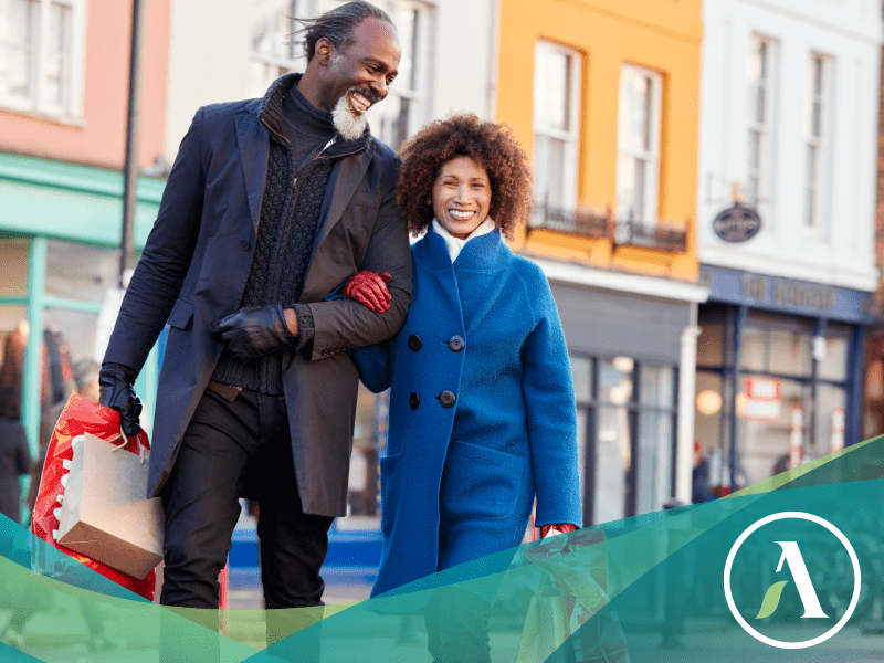 Happy black couple walkd down the street arm in arm holding shopping bags.