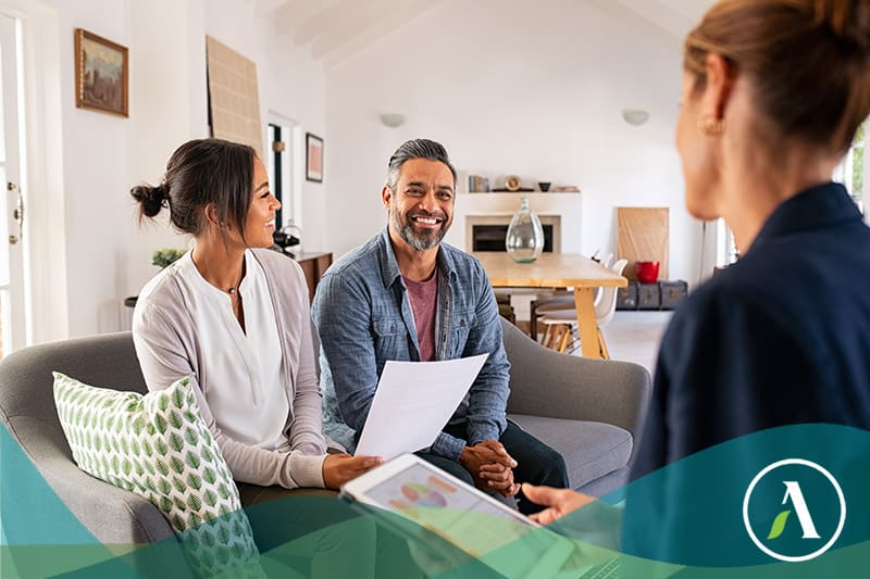Happy mature couple discussing investments with financial broker during meeting at home. Happy middle eastern man and hispanic woman discussing about financial planning with consultant at home. Financial consultant presenting new investment plan to smiling mature couple at home.