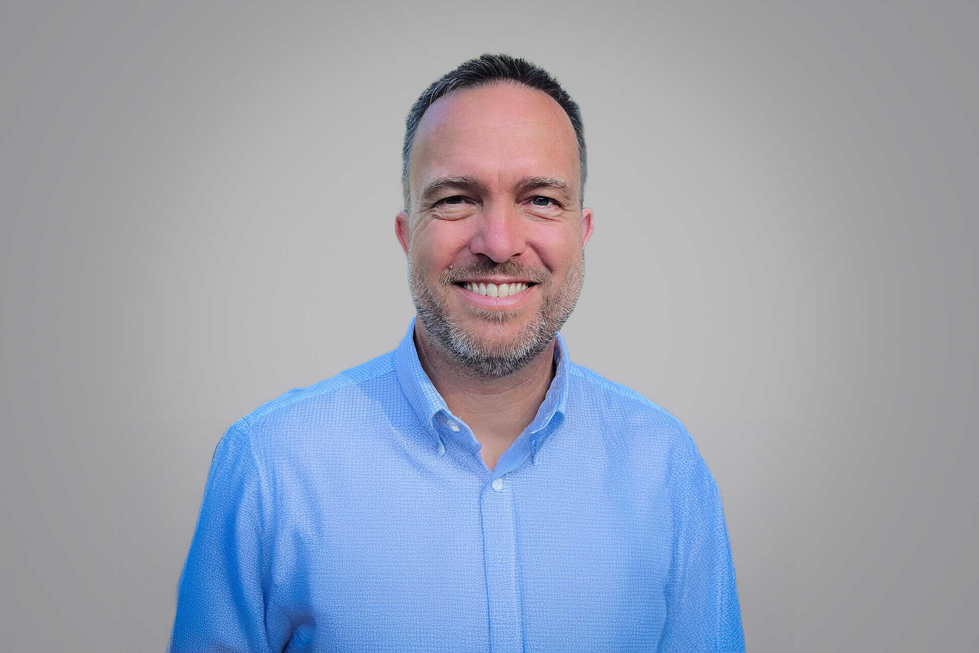 Brian Koning smiles at the camera in a blue shirt.