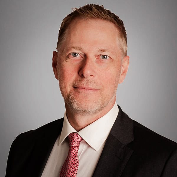 Mark Beck smiles at the camera in a black suit.
